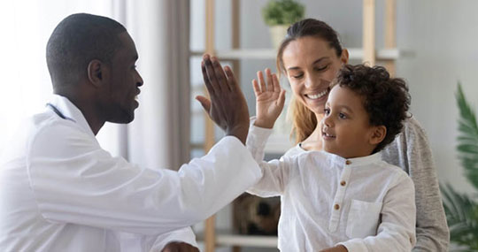 mother, father and little boy highfiving indoors