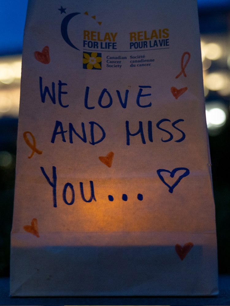A glowing luminary with a message on the bag that says, “We love and miss you.” 