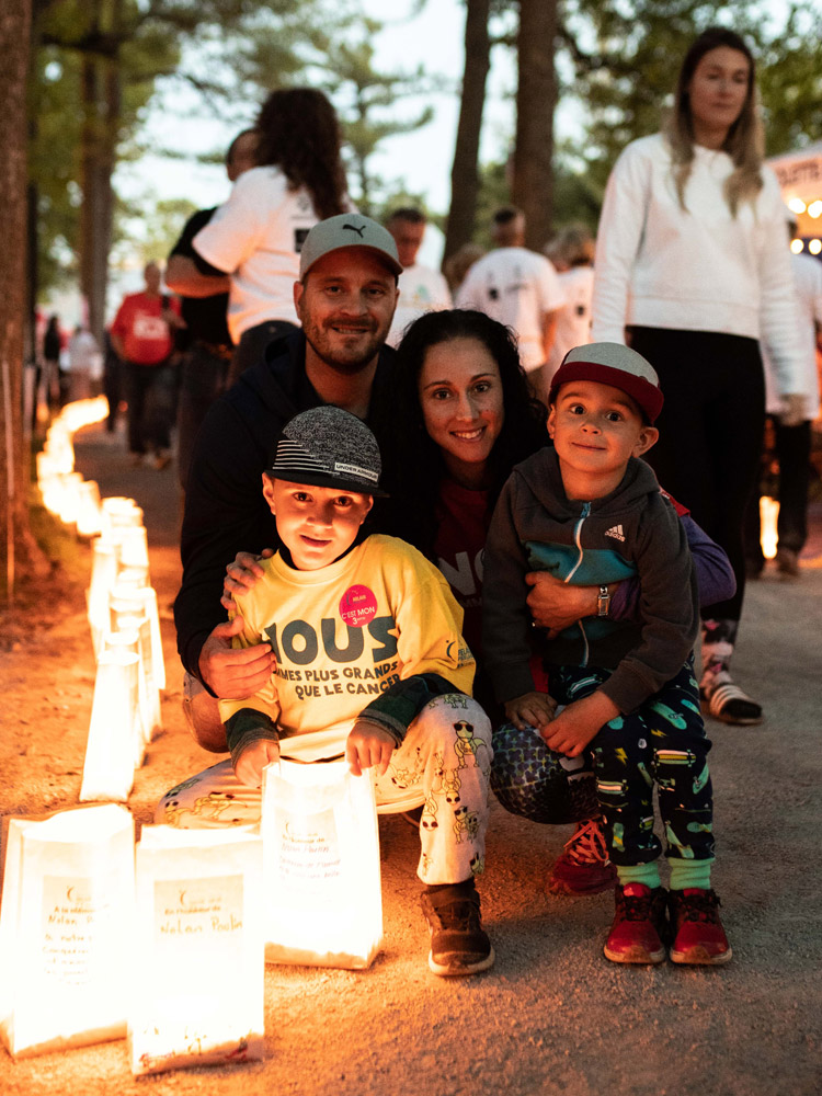 Une famille de quatre personnes souriant près d'un luminaire illuminé lors du Relais. 