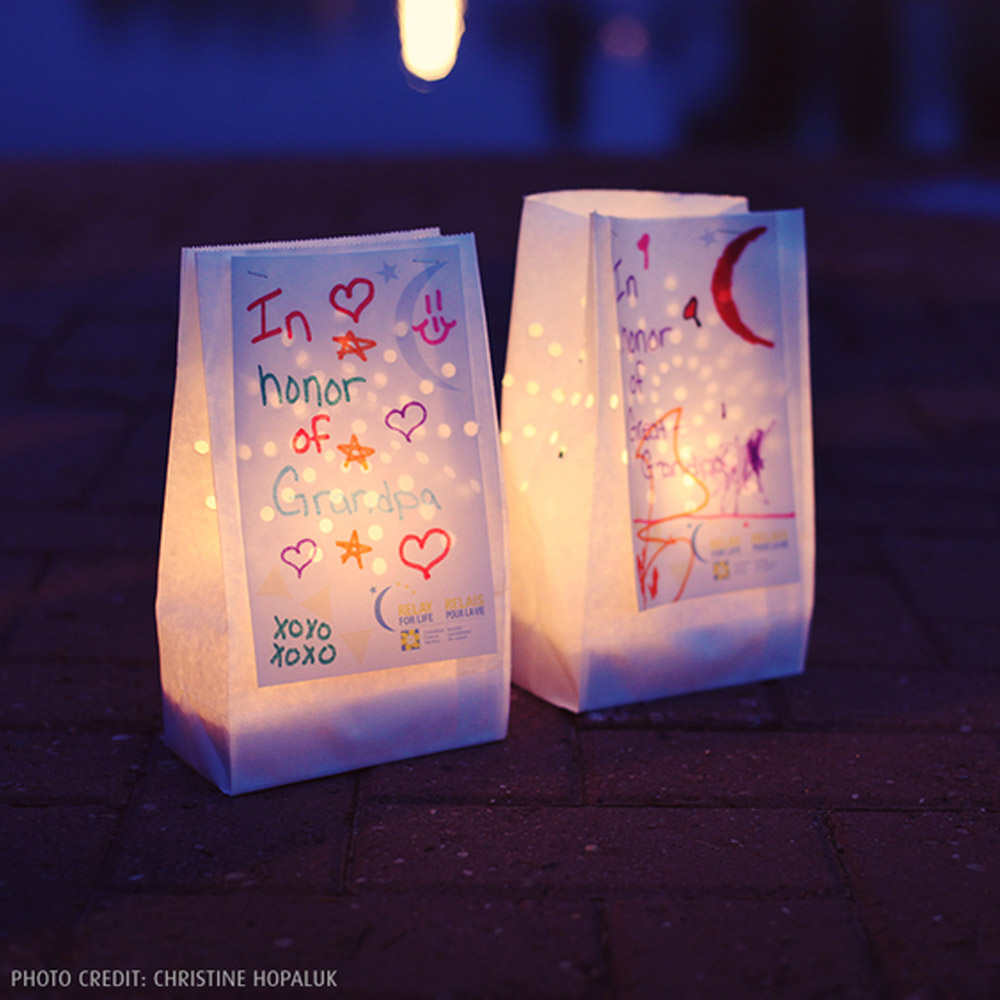 A glowing luminary with a message on the bag that says, “In honor of grandpa.” 