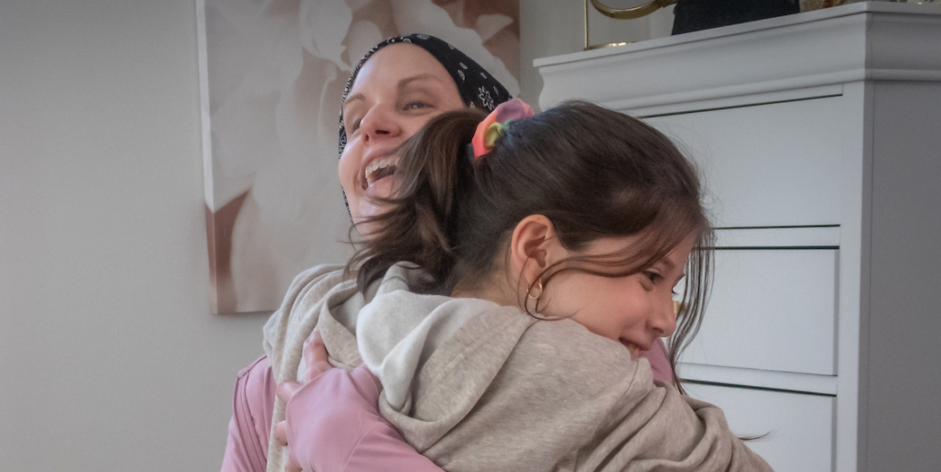 A woman and a young girl hugging and smiling